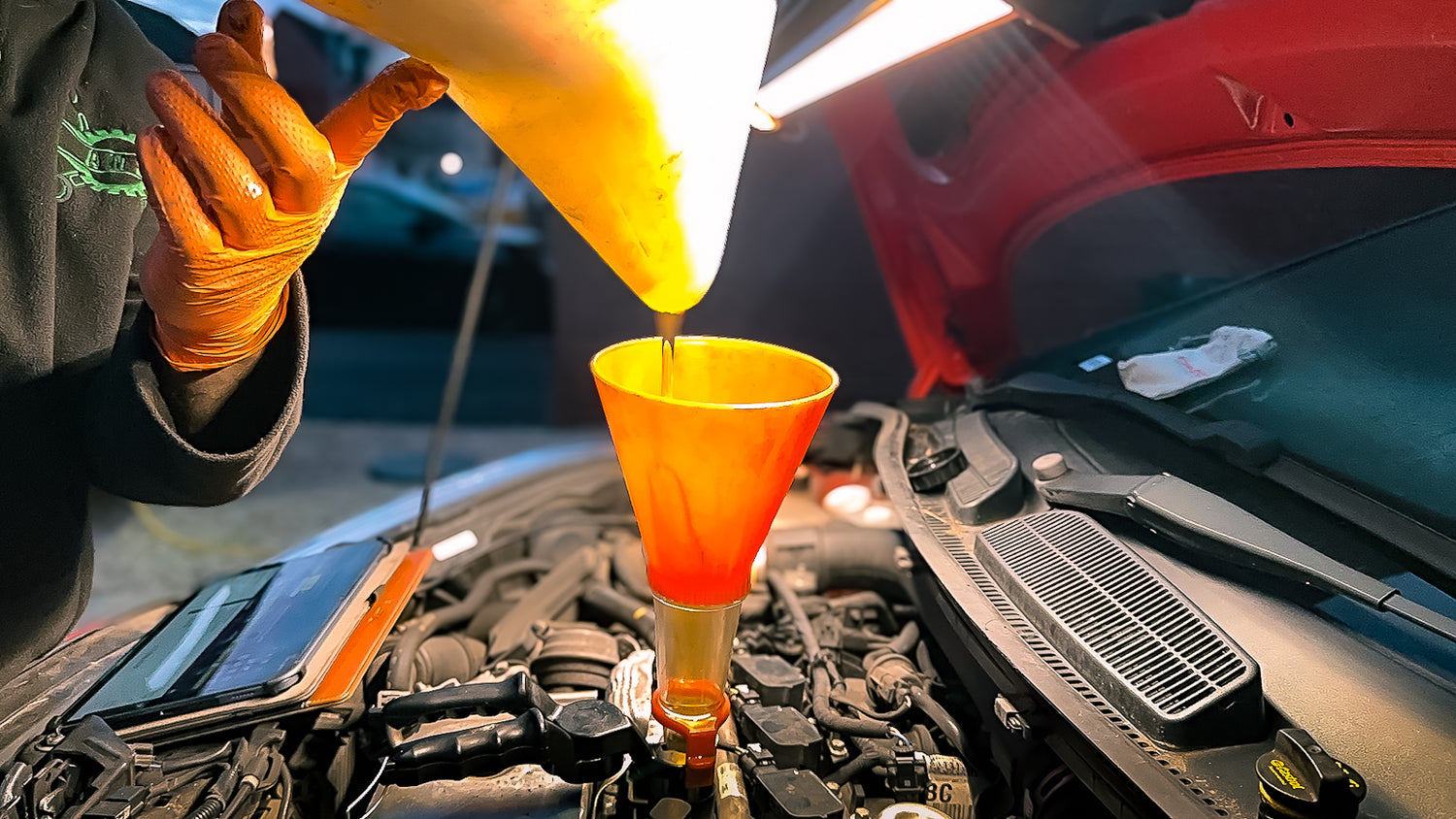 mechanic pouring oil into orange funnel